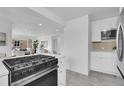 Open-concept kitchen featuring a gas range, white cabinets, and seamless flow into the living area at 5345 E Thrill Pl, Denver, CO 80207