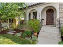 View of the front entrance with a decorative wooden door, portico, and manicured landscaping at 1376 S Clayton St, Denver, CO 80210