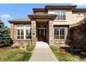 Inviting front entrance featuring a brick facade, double doors, and manicured landscaping at 9586 Silent Hills Ln, Lone Tree, CO 80124