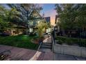 Charming home featuring a lush front yard, mature trees, and a welcoming entryway with stone steps and an iron gate at 1057 N Emerson St # B, Denver, CO 80218