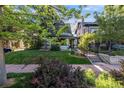 Charming home with a well-manicured lawn and mature trees, framed by a wrought iron fence and blooming bushes at 1057 N Emerson St # B, Denver, CO 80218