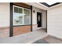 Inviting entrance with stylish black front door, white frame window, and stone landscaping at 11304 Elm Dr, Thornton, CO 80233