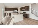 Open kitchen featuring a large island, stainless steel appliances, and modern dark-brown cabinetry at 4858 Astor Pl, Brighton, CO 80601