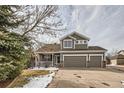 Two-story house with gray siding, three-car garage, and a covered porch. Lovely landscaping at 7395 Slate Ct, Castle Rock, CO 80108