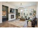 Bright living room featuring a stone fireplace, hardwood floors, large windows, and modern chandelier at 16392 Spanish Peak Way, Broomfield, CO 80023