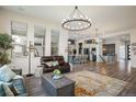Open concept living room with hardwood floors, a modern chandelier, and access to kitchen at 16392 Spanish Peak Way, Broomfield, CO 80023