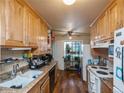 Galley kitchen featuring warm wood cabinets, double sink, and bright natural light at 300 S Simms St, Lakewood, CO 80228