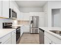 Clean kitchen features white cabinets, stainless appliances and grey backsplash at 485 Interlocken Blvd # 102, Broomfield, CO 80021