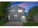 Charming two-story home with a gray exterior, well-manicured lawn, and attached two-car garage during dusk at 1464 Spotted Owl Way, Highlands Ranch, CO 80129