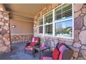 Inviting front porch with stone columns, comfortable seating, and decorative accents at 6638 S Tibet Ct, Aurora, CO 80016