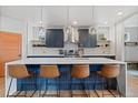 Modern kitchen features an island with seating, stainless steel appliances, and stylish pendant lighting at 2533 N Emerson St, Denver, CO 80205