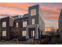 Modern two-story townhome featuring brick and stucco exterior, landscaping, and covered entry at sunset at 5438 Valentia St, Denver, CO 80238