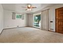 Bright living room features neutral carpet, white walls, large window, ceiling fan, and a wooden front door at 1803 Graves Ct, Northglenn, CO 80233
