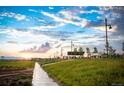 Scenic view of a community park with sidewalks, wildflowers, and mountain views at sunset at 21176 E 62Nd Dr, Aurora, CO 80019