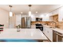Beautiful bright kitchen with stainless appliances, island with white countertop, and tile backsplash at 13961 E Marina Dr # 414, Aurora, CO 80014