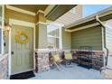 Inviting covered porch with chairs, decorative wreath, and stonework, offering a cozy entrance to the home at 3733 S Perth Cir # 101, Aurora, CO 80013