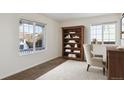 Cozy home office featuring natural light from two windows and a wooden bookshelf at 5928 E Conservation Dr, Frederick, CO 80504