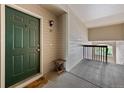 Condo entrance with a green door, wooden side table, and stairway at 9518 W San Juan Cir # 307, Littleton, CO 80128