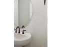 A simple yet clean powder room, featuring a modern oval mirror and dark fixtures at 8386 Cokedale Cir, Littleton, CO 80125