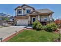 Beautiful two-story home featuring a manicured lawn, stone accents, and a welcoming front porch at 16352 E 104Th Way, Commerce City, CO 80022