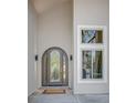 Grand front door with arched glass panels flanked by modern sconces and a side window at 6054 S Akron Way, Greenwood Village, CO 80111