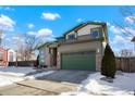 Two-story house with green garage door and snow-covered front yard at 998 Eaton St, Lakewood, CO 80214