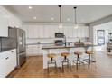 Modern kitchen featuring white cabinets, stainless steel appliances, a large island with barstool seating, and hardwood floors at 6506 Merrimack Dr, Castle Pines, CO 80108