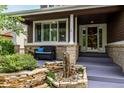 Inviting covered porch with a cozy bench, decorative brick, and stone garden area at 8410 S Oak St, Littleton, CO 80127