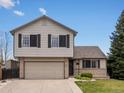 Charming two-story home featuring an attached two-car garage, manicured lawn, and brick accents at 5204 S Parfet Way, Littleton, CO 80127