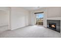 Cozy living room with a fireplace, balcony access and neutral carpet at 4100 Albion St # 617, Denver, CO 80216