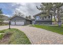 Inviting exterior features a well-maintained lawn, charming landscaping, and a brick driveway leading to the home's entrance and garage at 5254 W Oberlin Dr, Denver, CO 80235