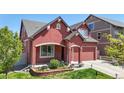 Stylish red two-story home featuring beautiful landscaping and a convenient two-car garage at 18009 E 47Th Pl, Denver, CO 80249