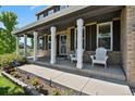 Inviting front porch with classic columns, comfortable seating, and landscaped flower bed at 19653 E Ida Dr, Aurora, CO 80015