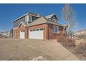 Three-car garage on a brick home with gray siding and a wide driveway at 7119 S Riviera St, Aurora, CO 80016