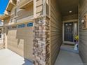 A welcoming front door is flanked by a stone pillar, a black front door, and neutral siding at 16658 Prospect Ln, Broomfield, CO 80023