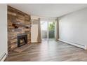 Inviting living room features a stone fireplace, wood-style flooring, and a sliding glass door to a balcony at 10150 E Virginia Ave # 7-204, Denver, CO 80247