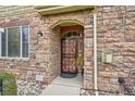 Close-up of front door with decorative ironwork and stone surround at 15496 W 66Th Dr # G, Arvada, CO 80007