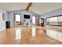 Bright, spacious living room with tiled floors, large windows, and a vaulted ceiling with wood beams at 1632 S County Road 137, Bennett, CO 80102