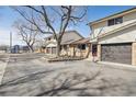 View of the home featuring a brick facade, a two-car garage and mature landscaping at 4655 Independence St # 3, Wheat Ridge, CO 80033