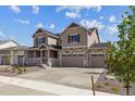 Charming two-story home featuring a three-car garage, stone accents, and a cozy front porch at 25214 E Warren Pl, Aurora, CO 80018