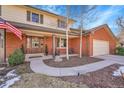 Inviting front porch with wood pillars and double front doors, complemented by an American flag at 5158 W Lake Pl, Littleton, CO 80123