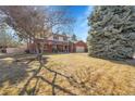 Beautiful two-story home with red brick, a lush green lawn, and mature trees in the front yard at 5158 W Lake Pl, Littleton, CO 80123