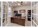 Inviting home office with glass French doors, built in bookcase, and large wooden desk at 2454 Ambience Ln, Castle Rock, CO 80109