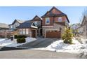 Two-story home with stone and shingle accents, attached garage, basketball hoop, and snow-covered landscaping at 1128 Starglow Pl, Highlands Ranch, CO 80126