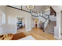 Grand foyer featuring high ceilings, an elegant chandelier, and an open staircase with black and white railings at 7734 Terry Ct, Arvada, CO 80007