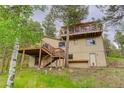 Backyard view with multiple wooden decks, a large yard, and an exterior door at 9209 William Cody Dr, Evergreen, CO 80439