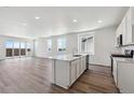 Open kitchen with sleek island, white cabinets, modern appliances, and hardwood floors at 19040 E 96Th Pl, Commerce City, CO 80022