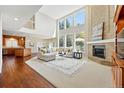 Spacious living room with a fireplace, tall windows, and hardwood floors that flow into the kitchen at 9556 Kemper Dr, Lone Tree, CO 80124