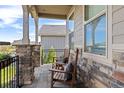 Inviting front porch featuring stone pillars, rocking chairs, and view of yard at 3214 Heron Lakes Pkwy, Berthoud, CO 80513