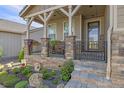 Front porch with stone pillars, metal railing, and flower planters at 3214 Heron Lakes Pkwy, Berthoud, CO 80513